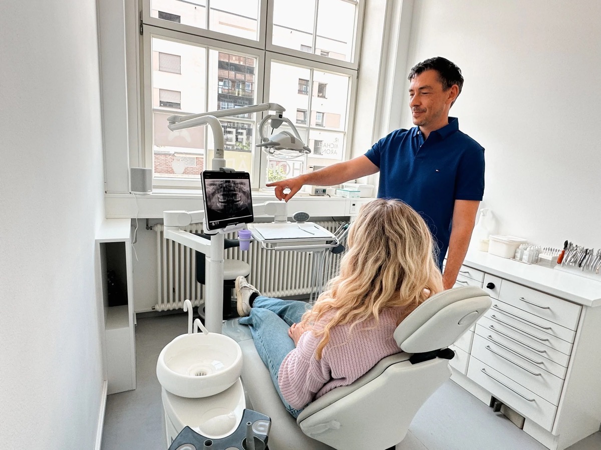 Zahnarzt Dr. Christoph Dippold erklärt einer Patientin mit einer Röntgenaufnahme die nächsten Behandlungsschritte auf einem Bildschirm in der Kieferorthopädie Praxis in Erlangen.