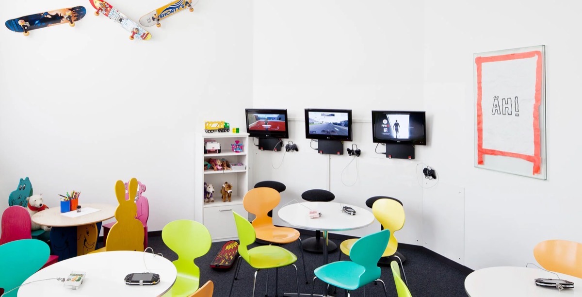 Spielcafé mit bunten Stühlen, Spielzeug, TV-Spielen und Wanddekoration im Kinderzimmer.